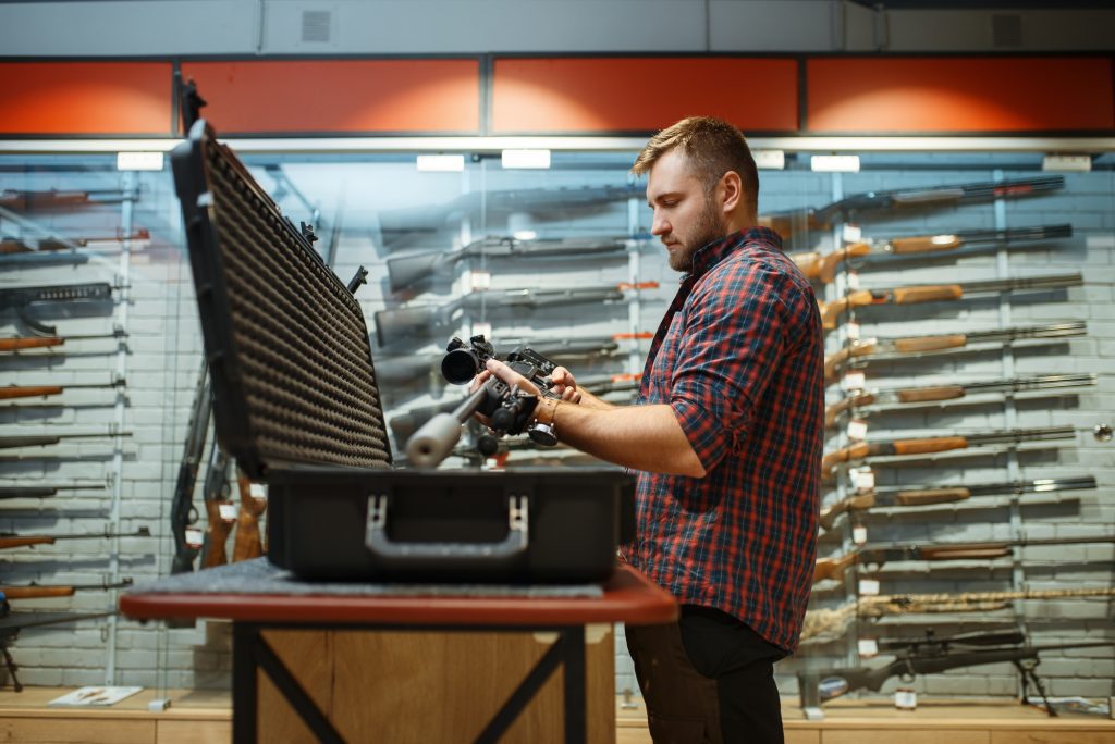 Man takes sniper rifle from the case in gun shop