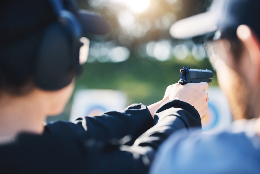 Man, woman and gun training with target, outdoor challenge and aim at police, army or security acad